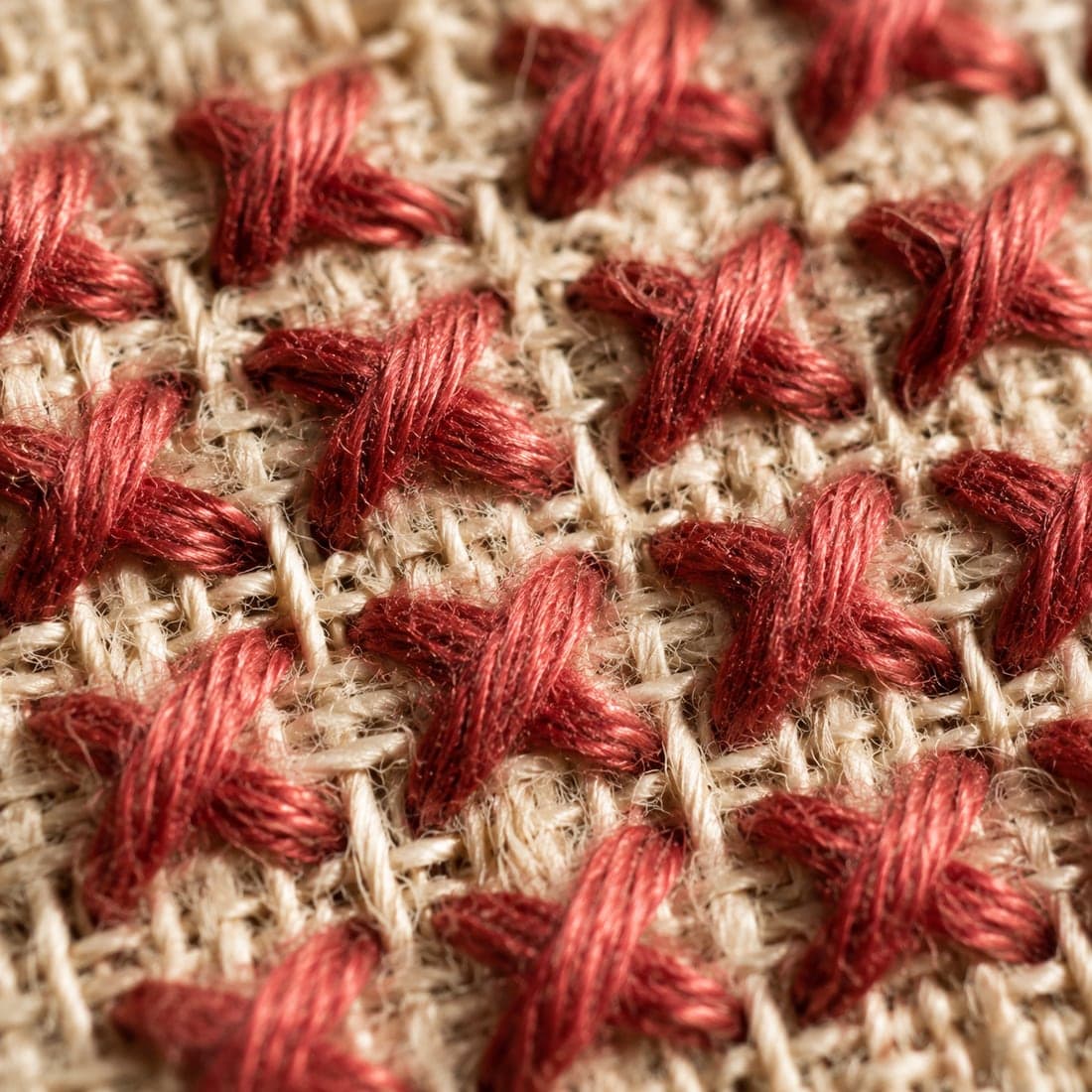 Macro view of cross-stitch on hand-woven linen